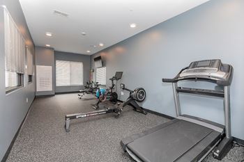 A home gym with a treadmill, rowing machine, and weights. at The Lumos Apartments, Ohio